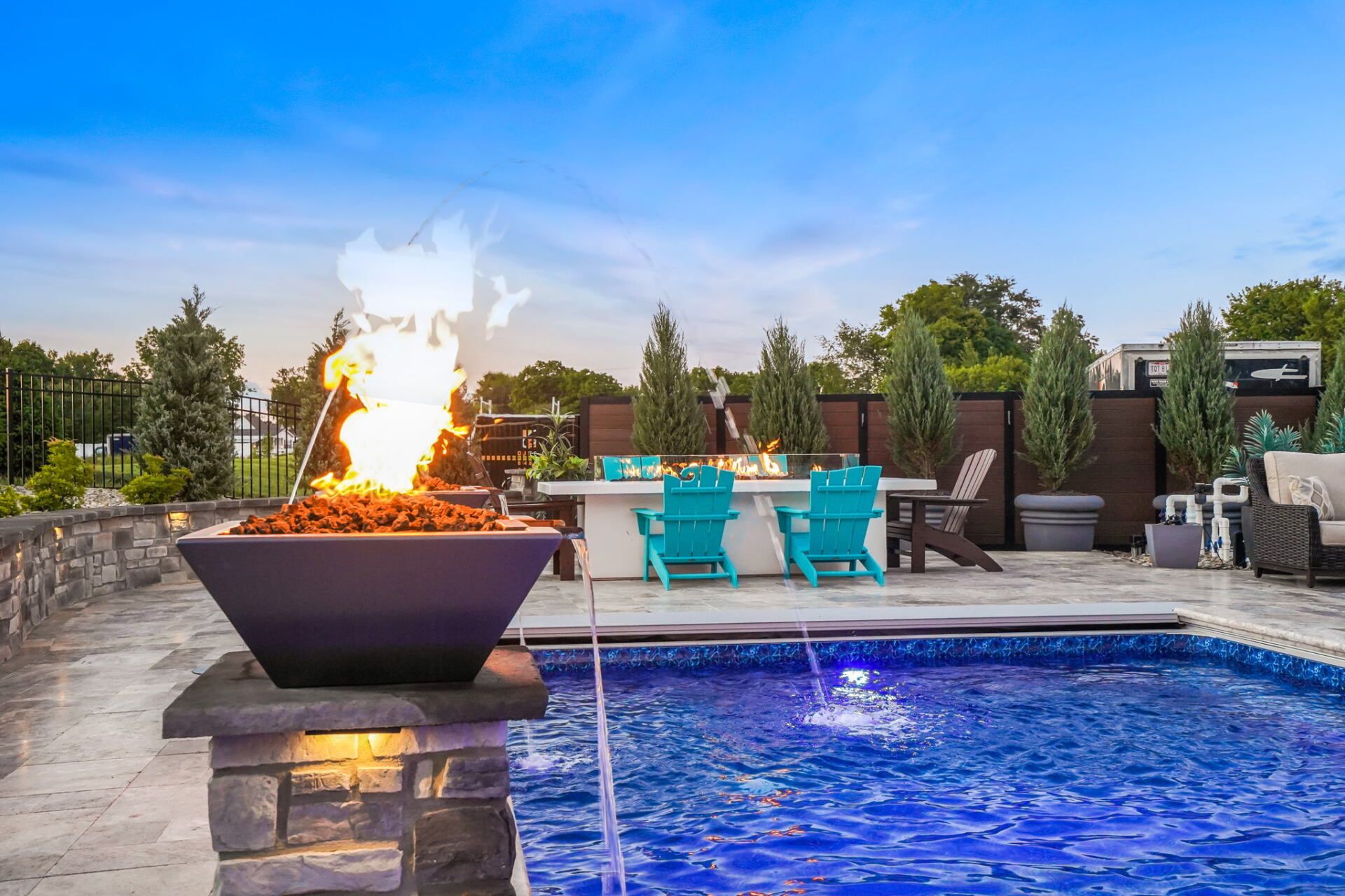 Rooftop pool with fire pit, turquoise lounge chairs, and evening city skyline