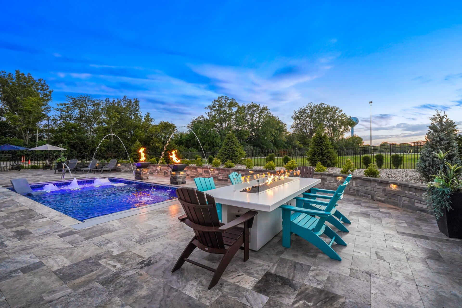 Backyard patio with pool, outdoor dining table, and turquoise chairs at dusk