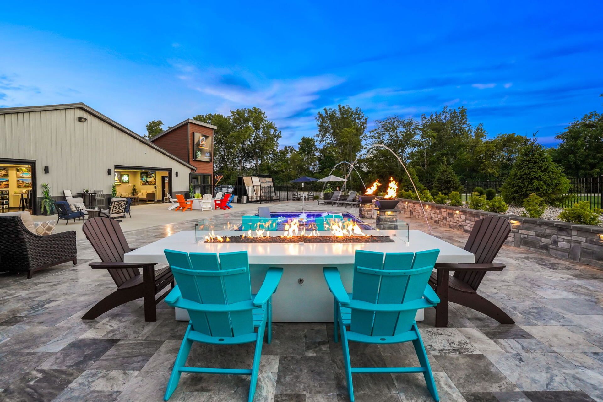 Outdoor patio with turquoise chairs around a fire pit and lounge seating at dusk