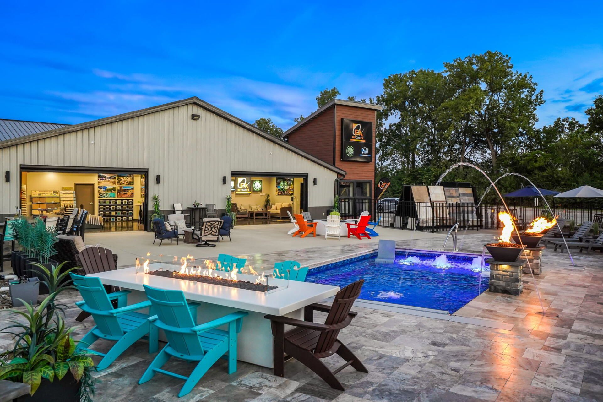 Backyard patio with turquoise chairs, lit pool, and modern house at dusk