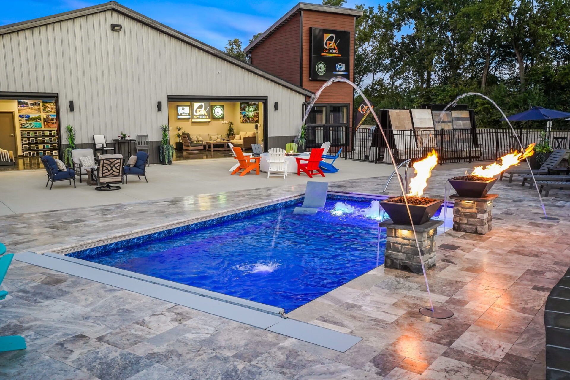 Backyard pool patio with fire bowls, lounge chairs, and a house at dusk