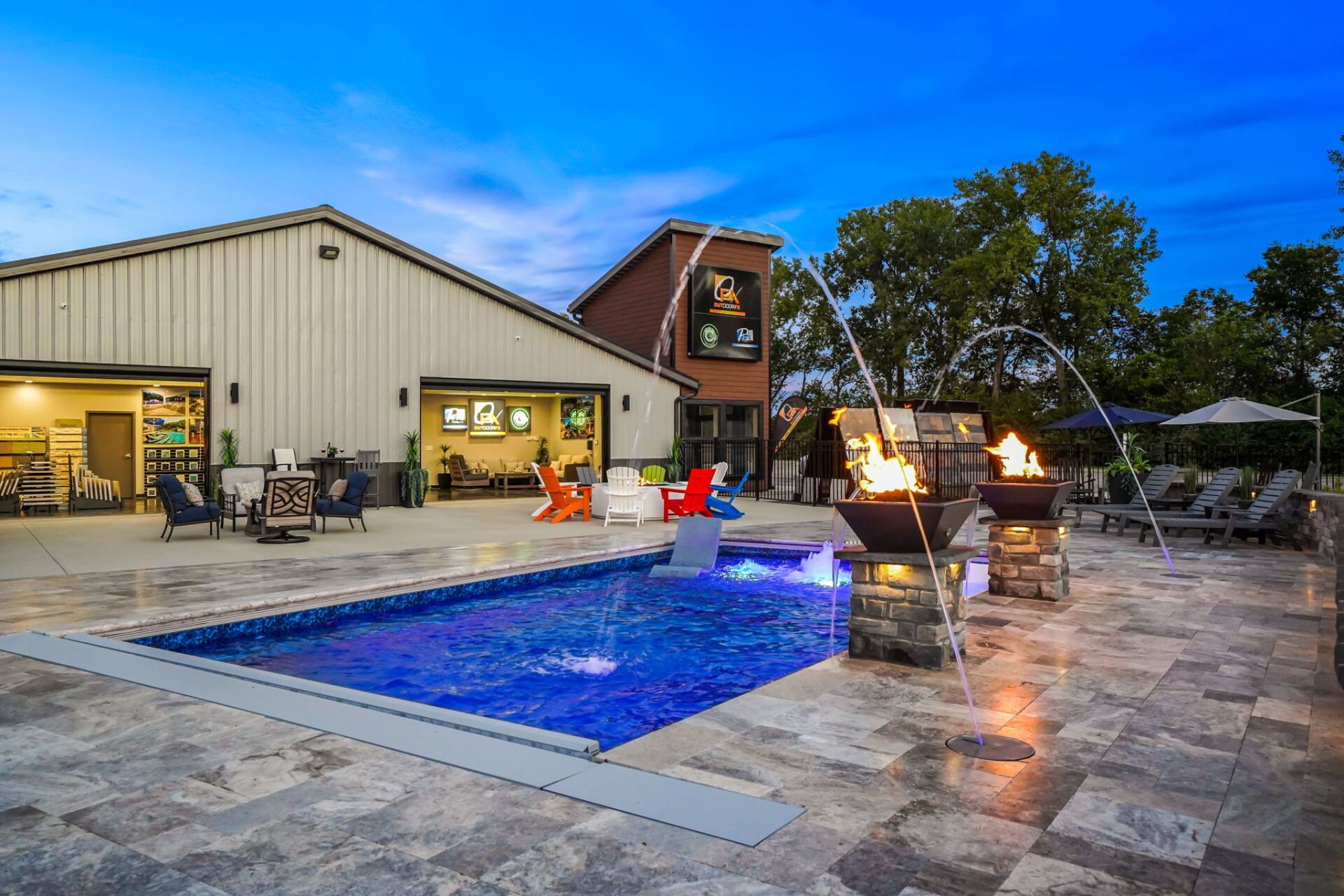 Backyard pool patio at dusk with lit fire pit, lounge chairs, and a house in the background