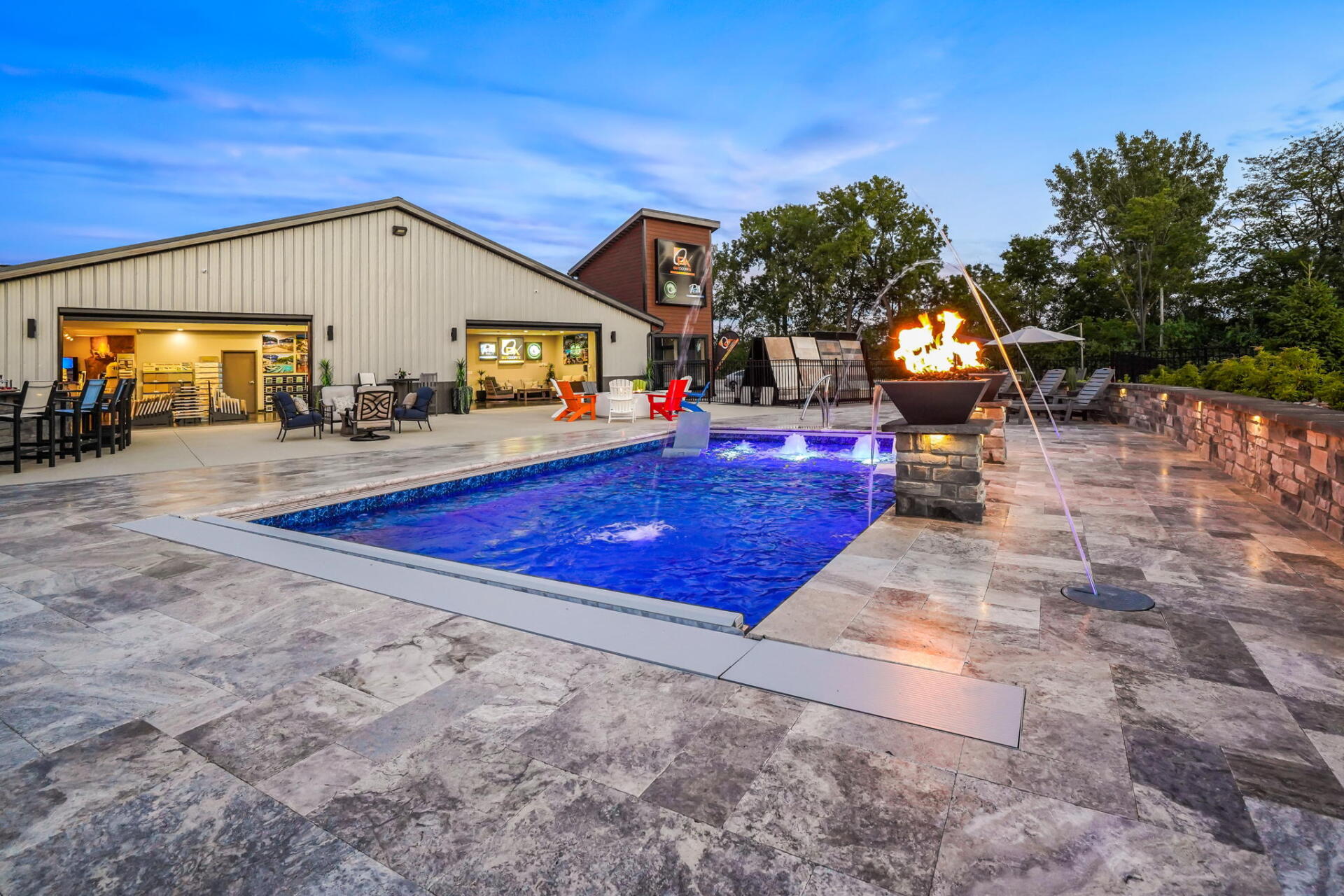 Backyard patio with lit pool, fire pit, and covered outdoor seating at dusk