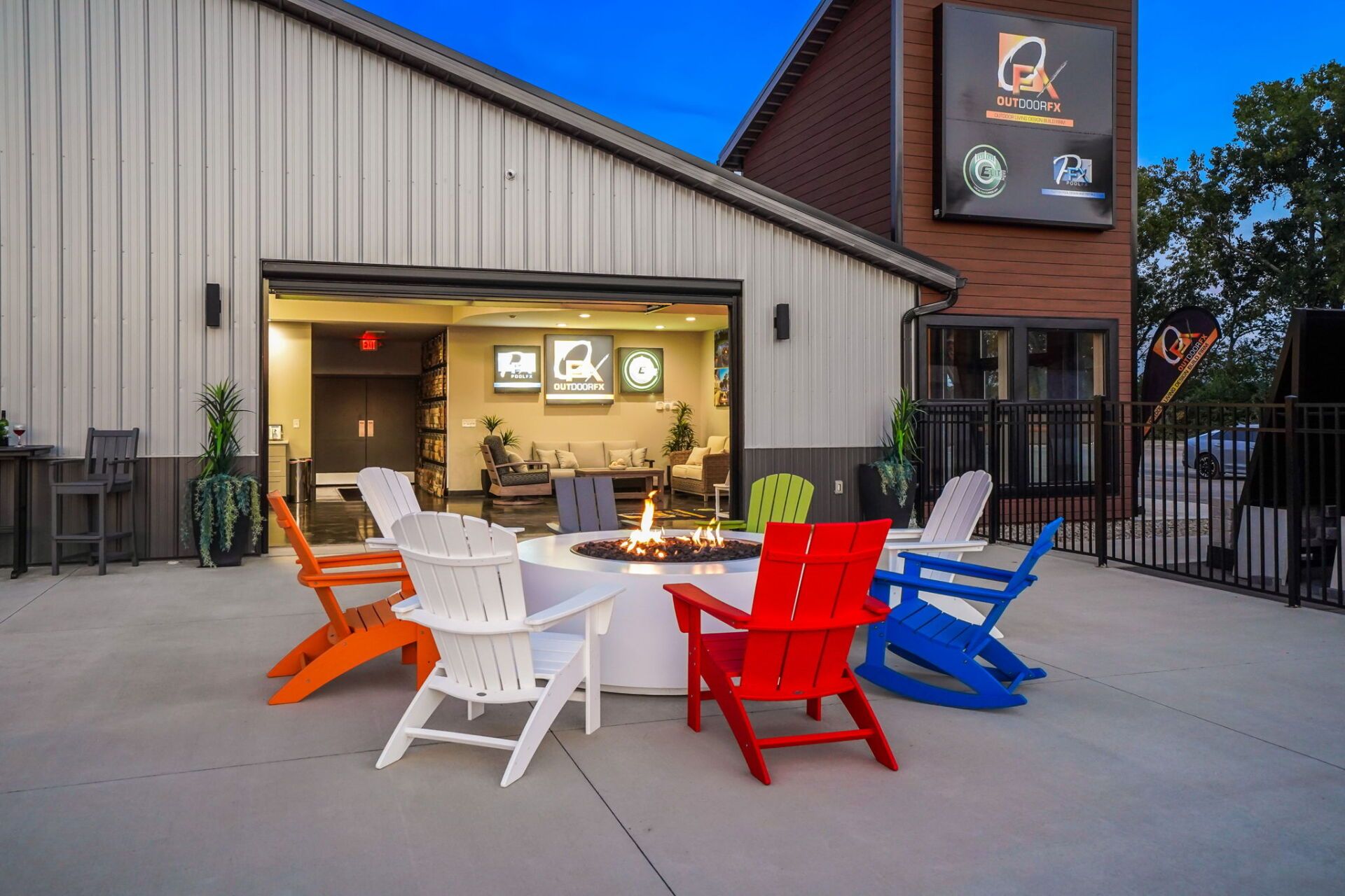 Outdoor patio with colorful Adirondack chairs around a fire pit beside a building.