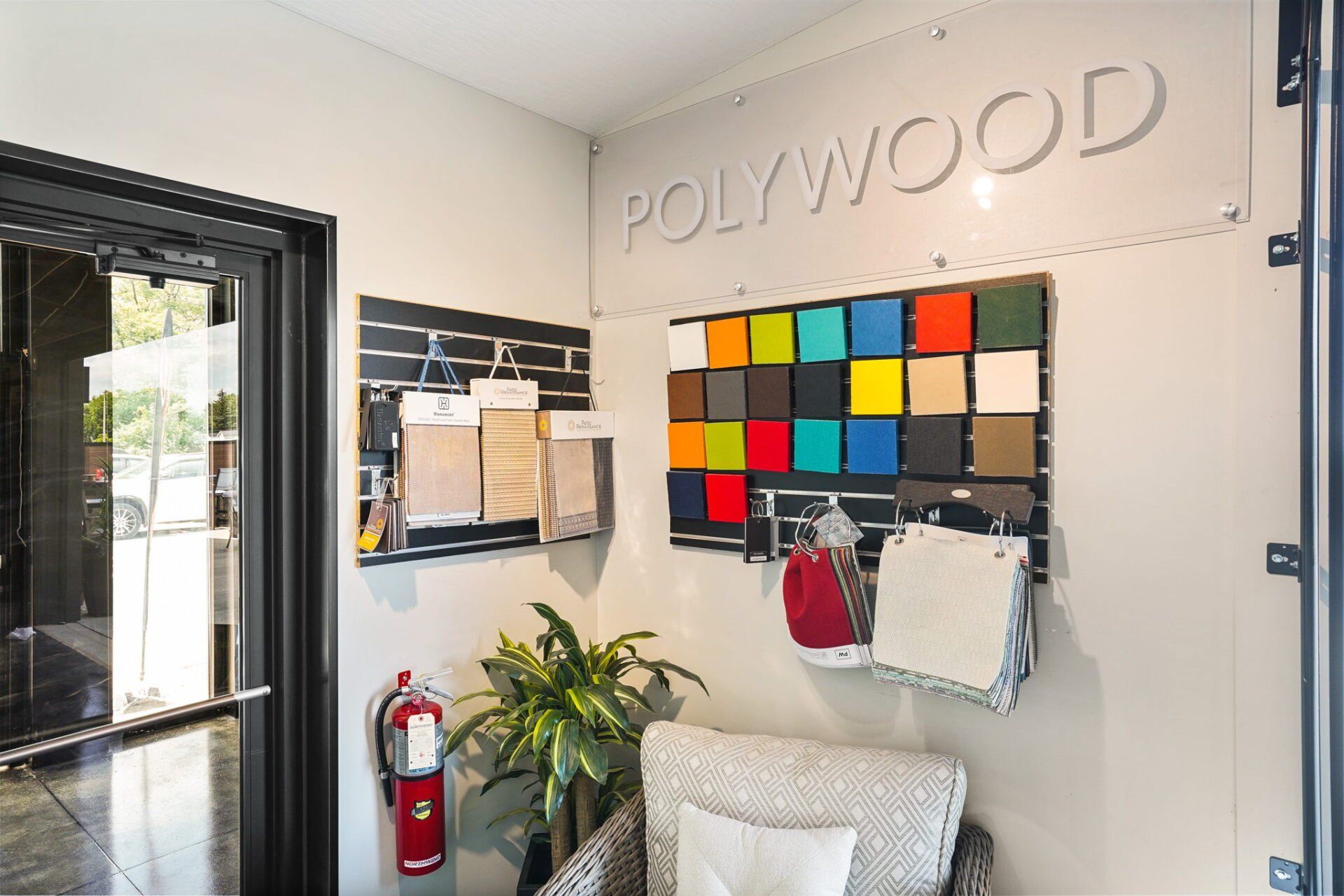 Interior office lobby with color swatches, bulletin board, potted plant, and fire extinguisher near an open door
