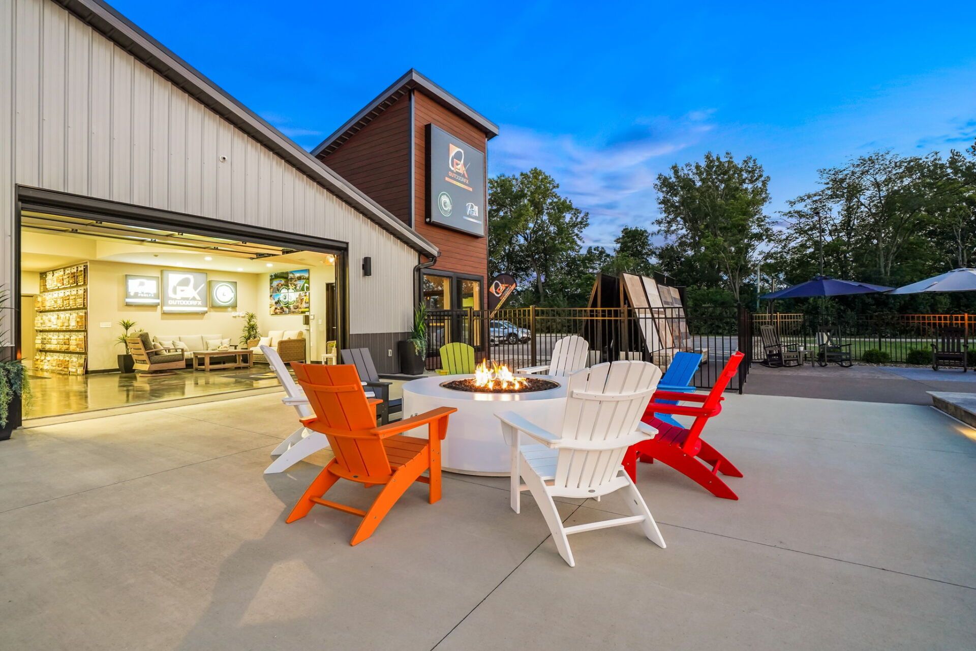 Colorful Adirondack chairs on a patio outside a lit building at dusk