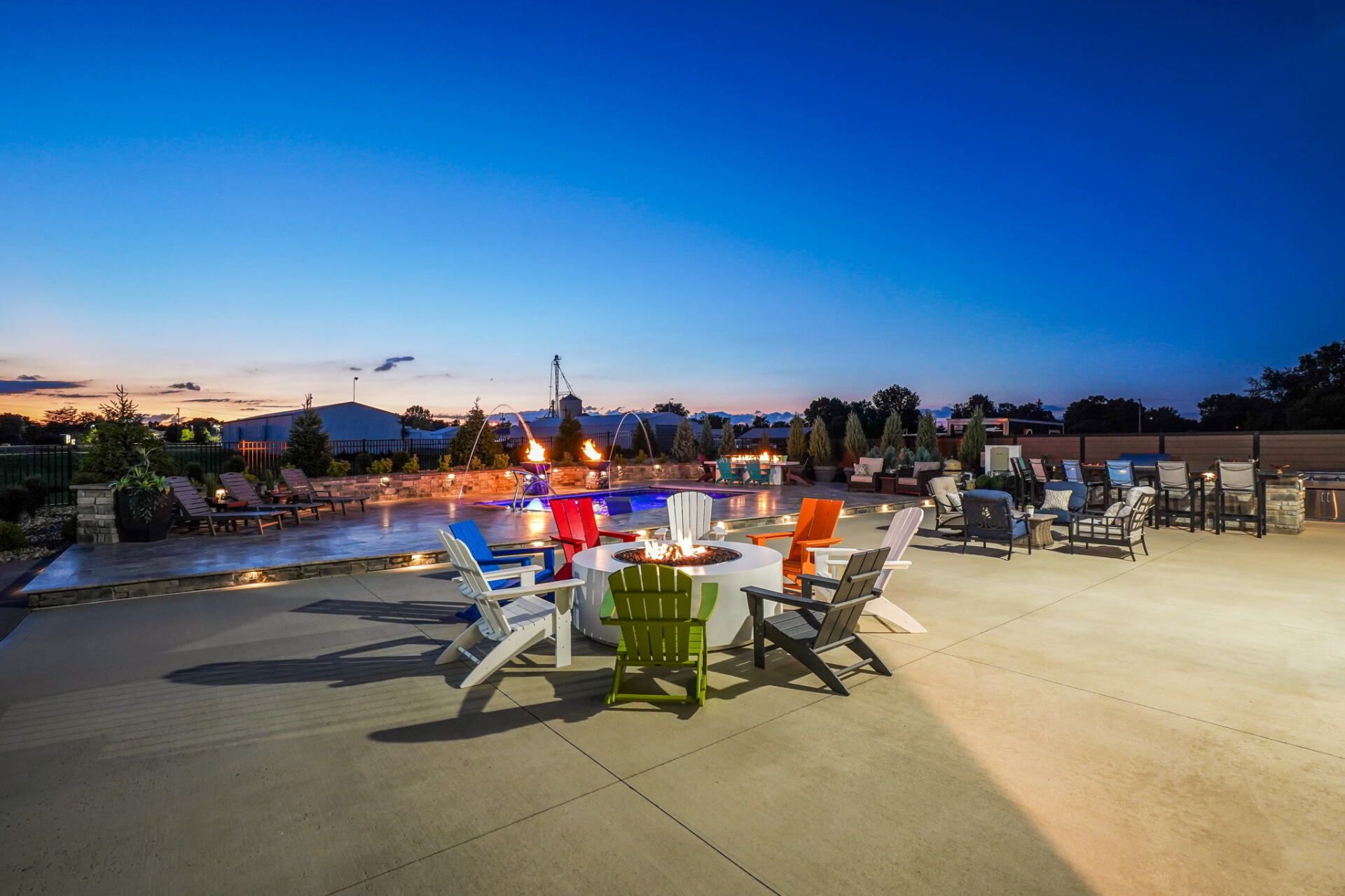 Outdoor dining area at dusk with tables, chairs, and city lights under a blue sky