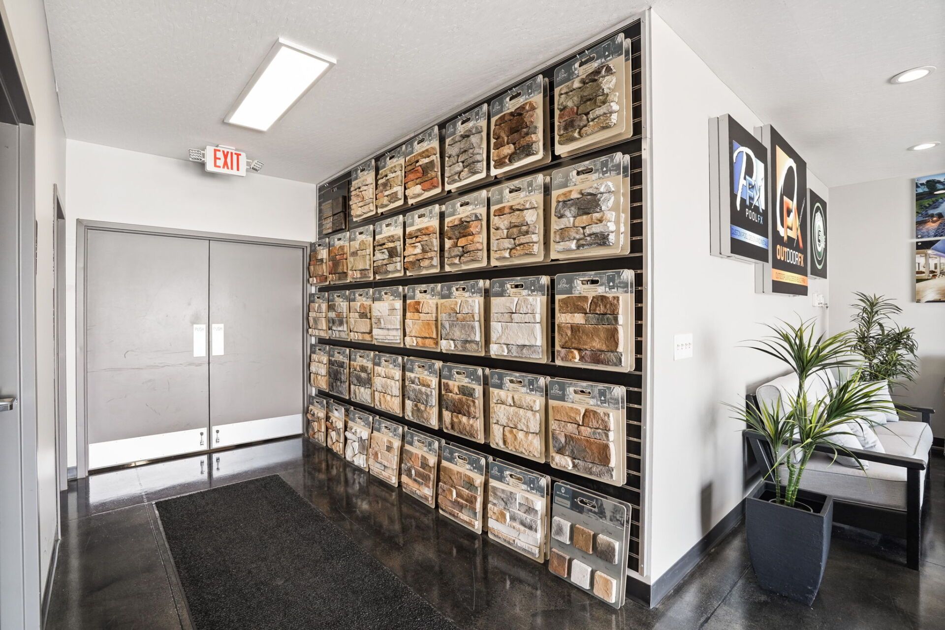 Office hallway with wall-mounted shoe boxes, double doors, black carpet, and a potted plant