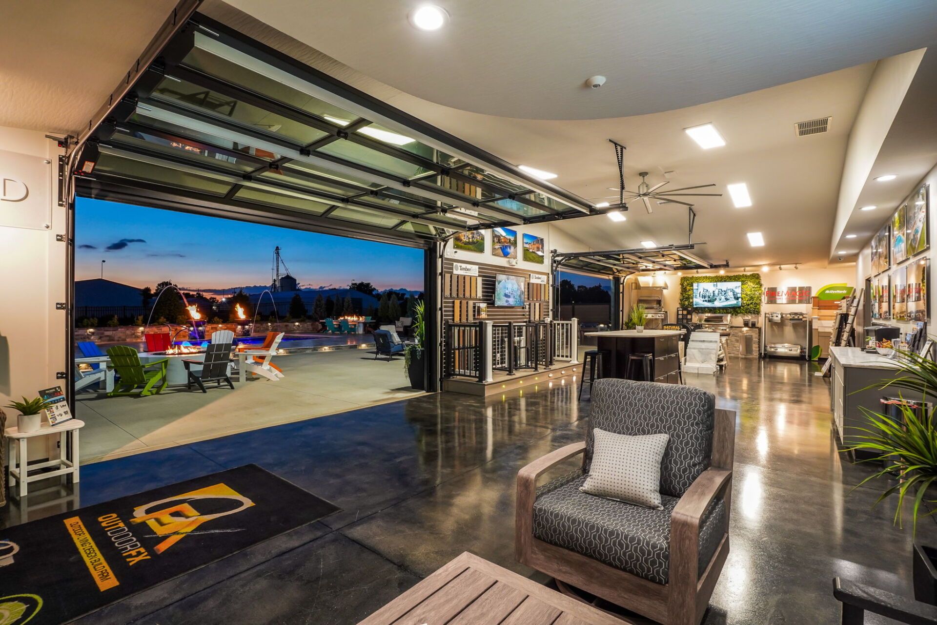Open-air restaurant patio at dusk with tables, bar, and city lights beyond the open garage door
