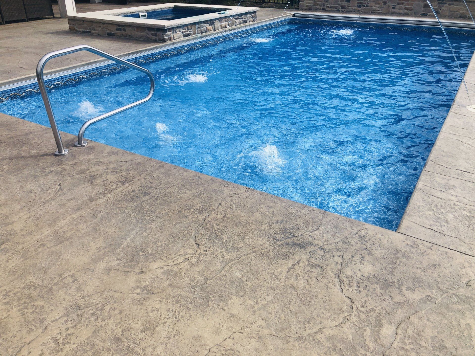 Outdoor swimming pool with blue water and a metal handrail by the deck