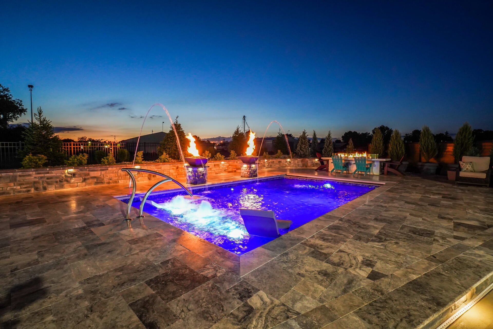 Illuminated blue fountain in a stone plaza at dusk, with a glowing pool and surrounding lights