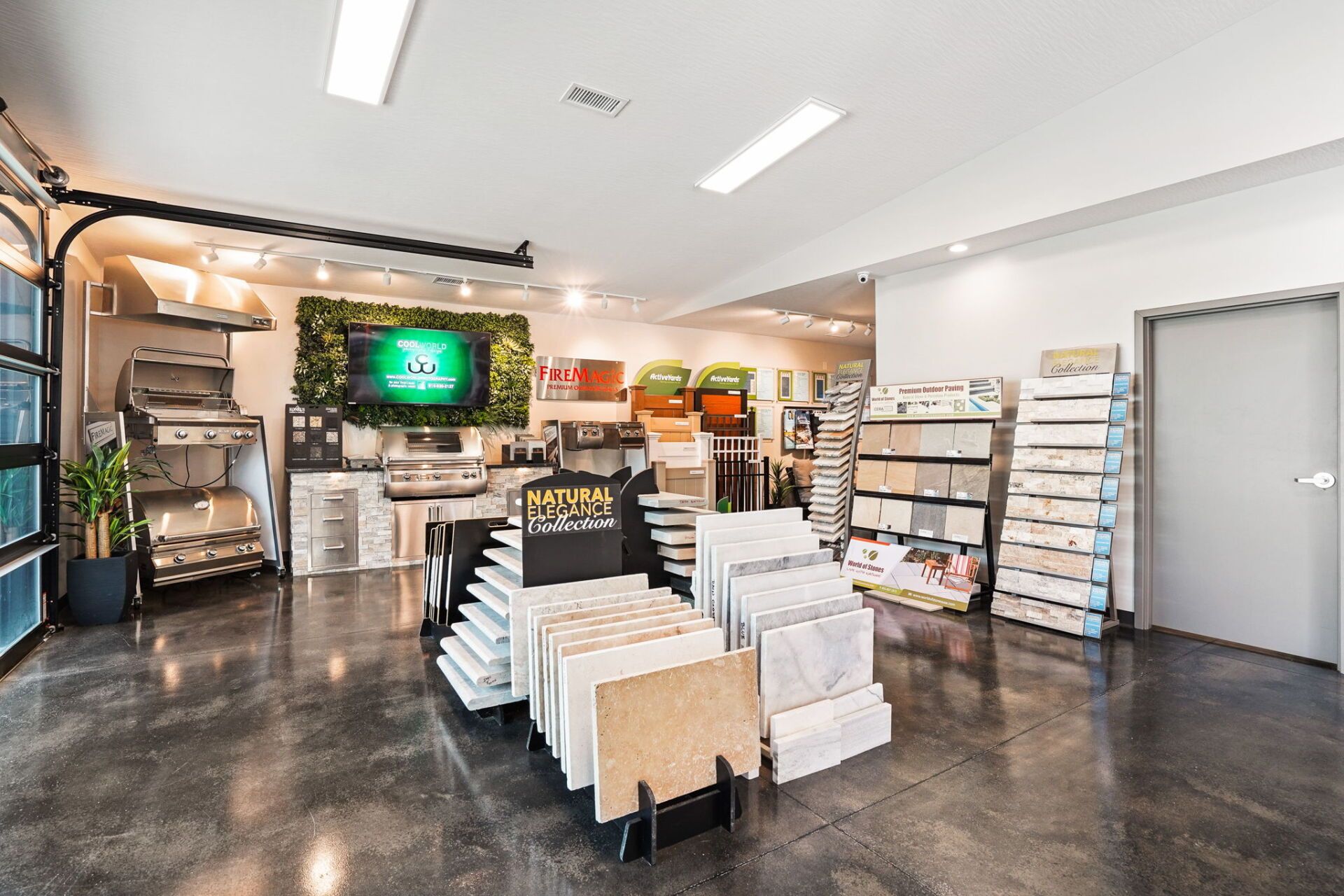 Bright retail showroom with shelves, stacked products, and a TV display on polished concrete floor.