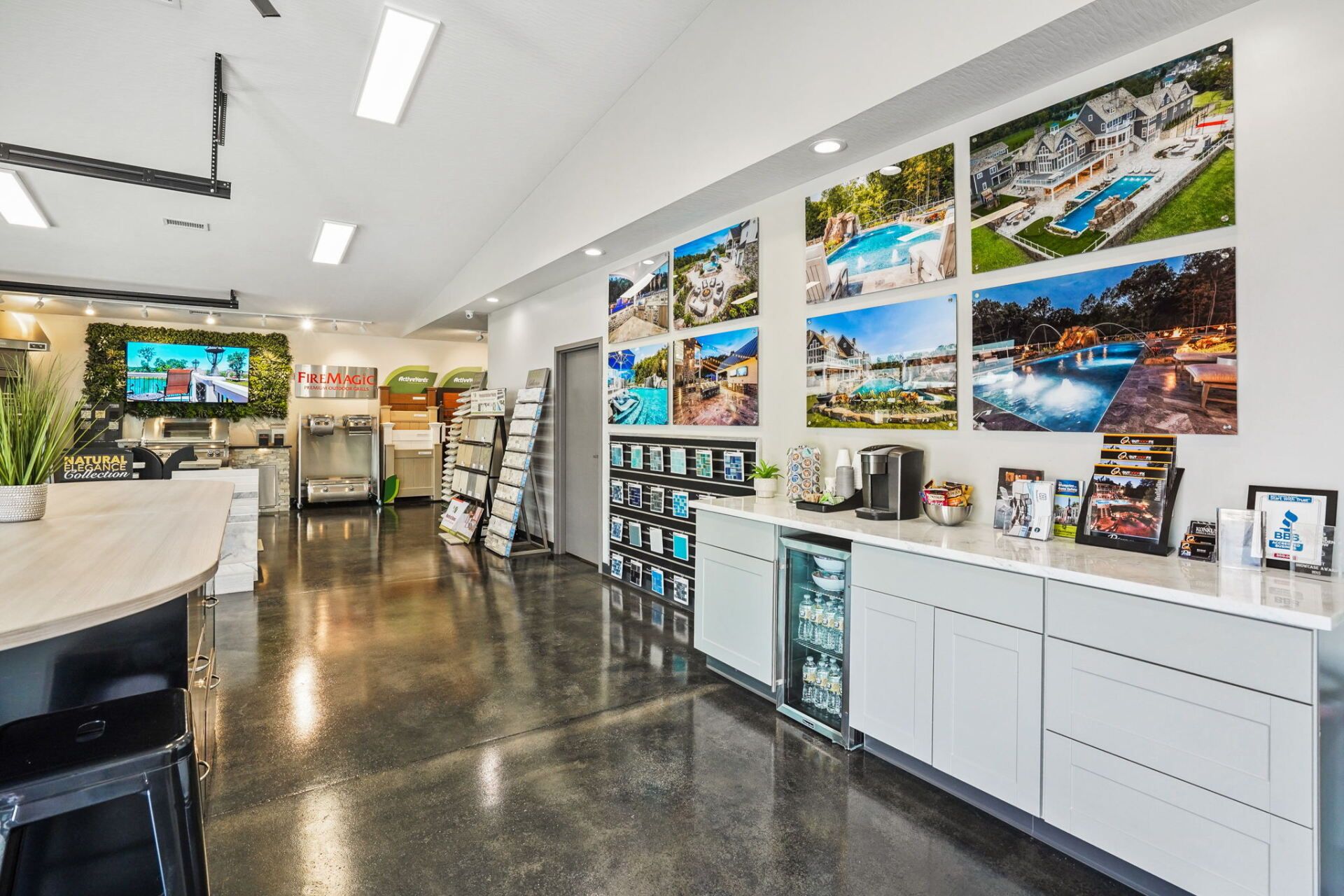 Bright office kitchenette with white cabinets, beverage station, and colorful travel photos on the wall