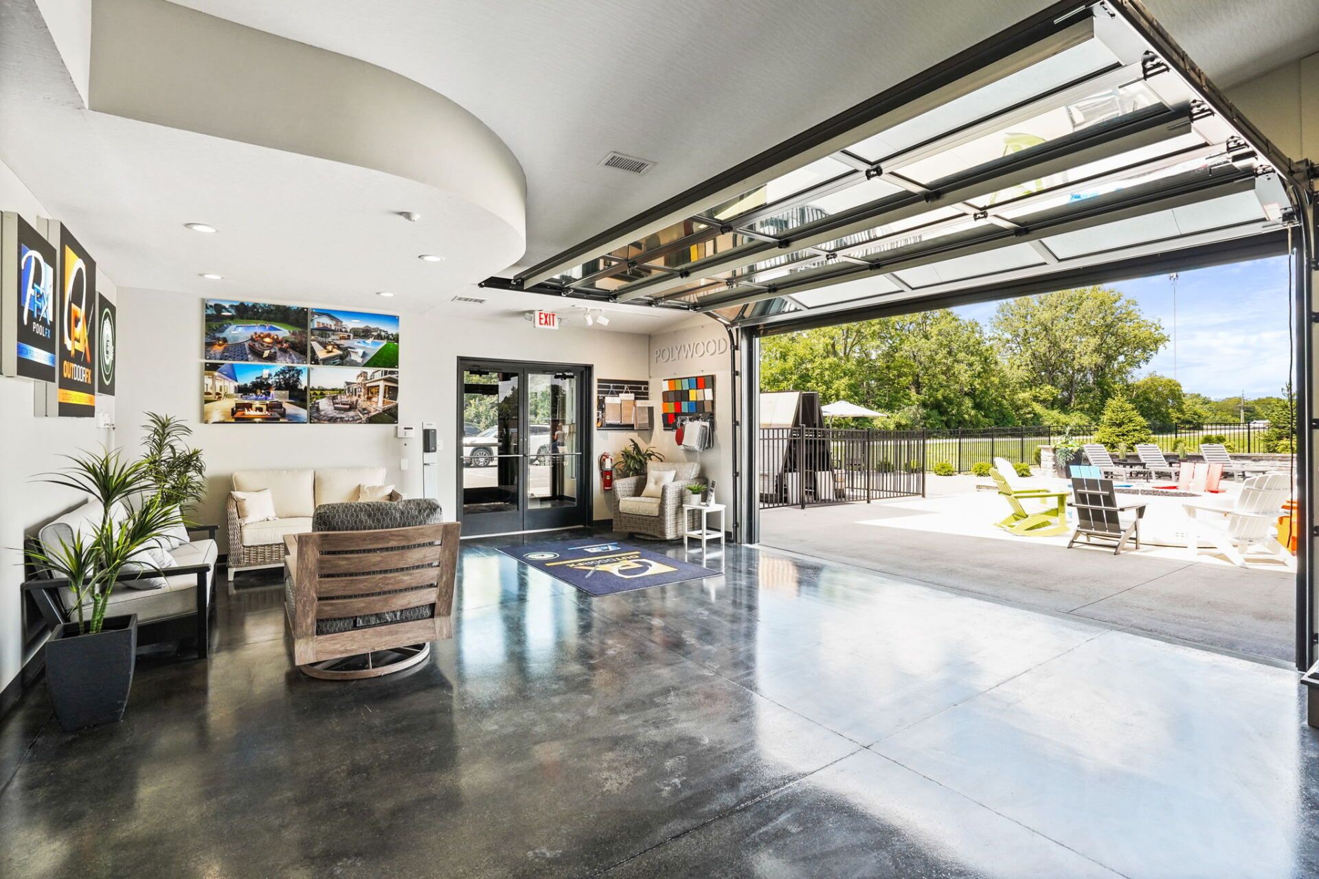 Modern patio with open garage-style doors, polished floor, artwork, and outdoor seating overlooking a sunny courtyard