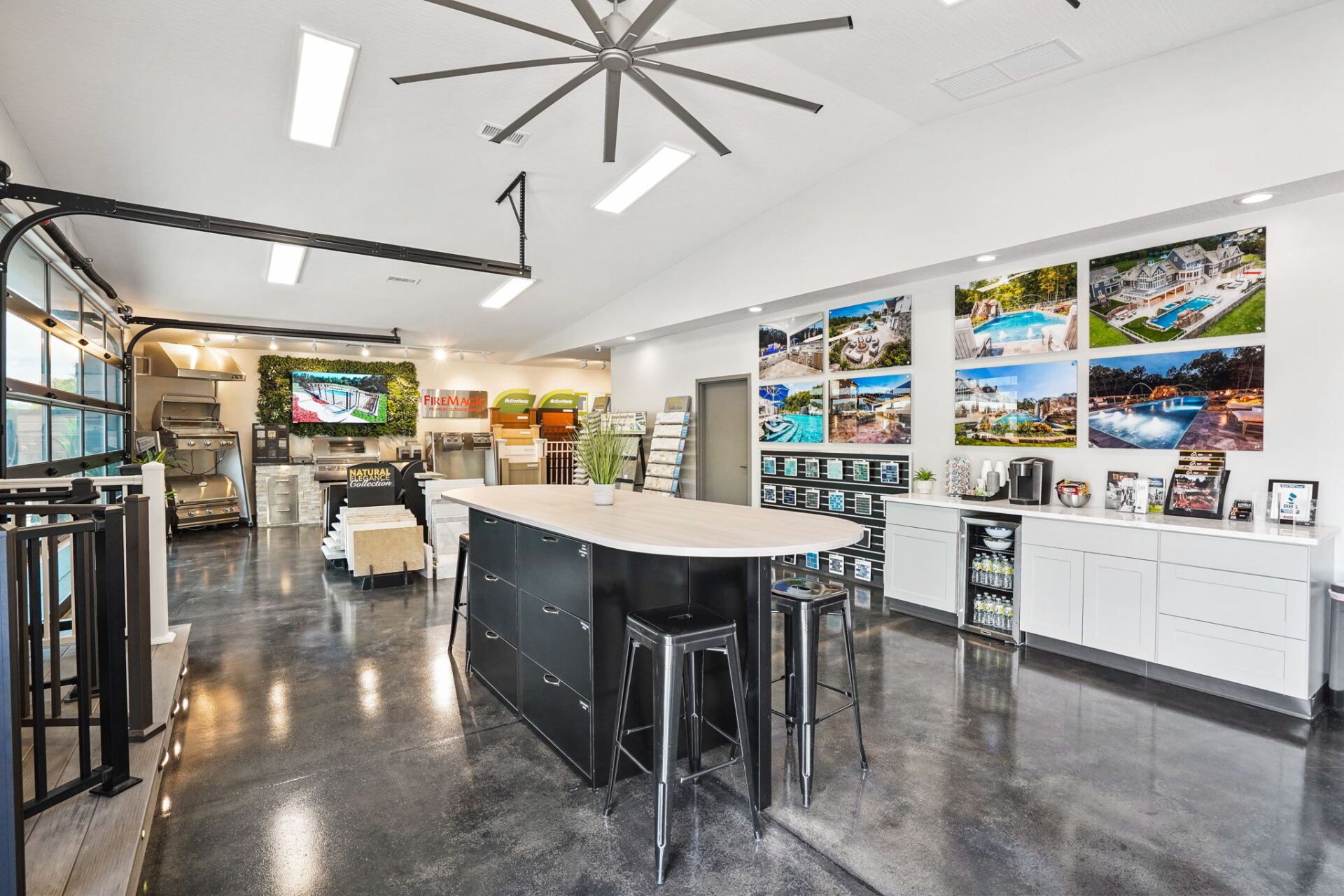 Modern showroom with glossy black floors, white tables, and colorful wall-mounted landscape displays.