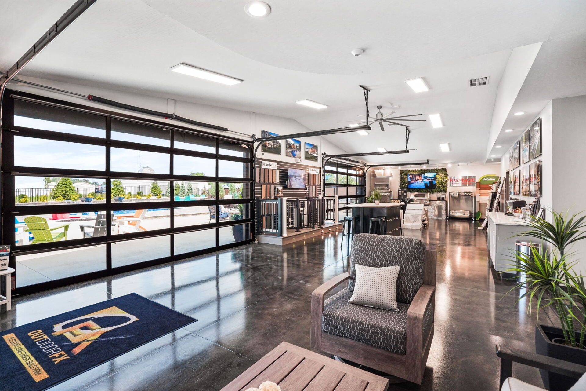 Bright modern showroom with glass garage door, seating area, and potted plants inside a polished showroom