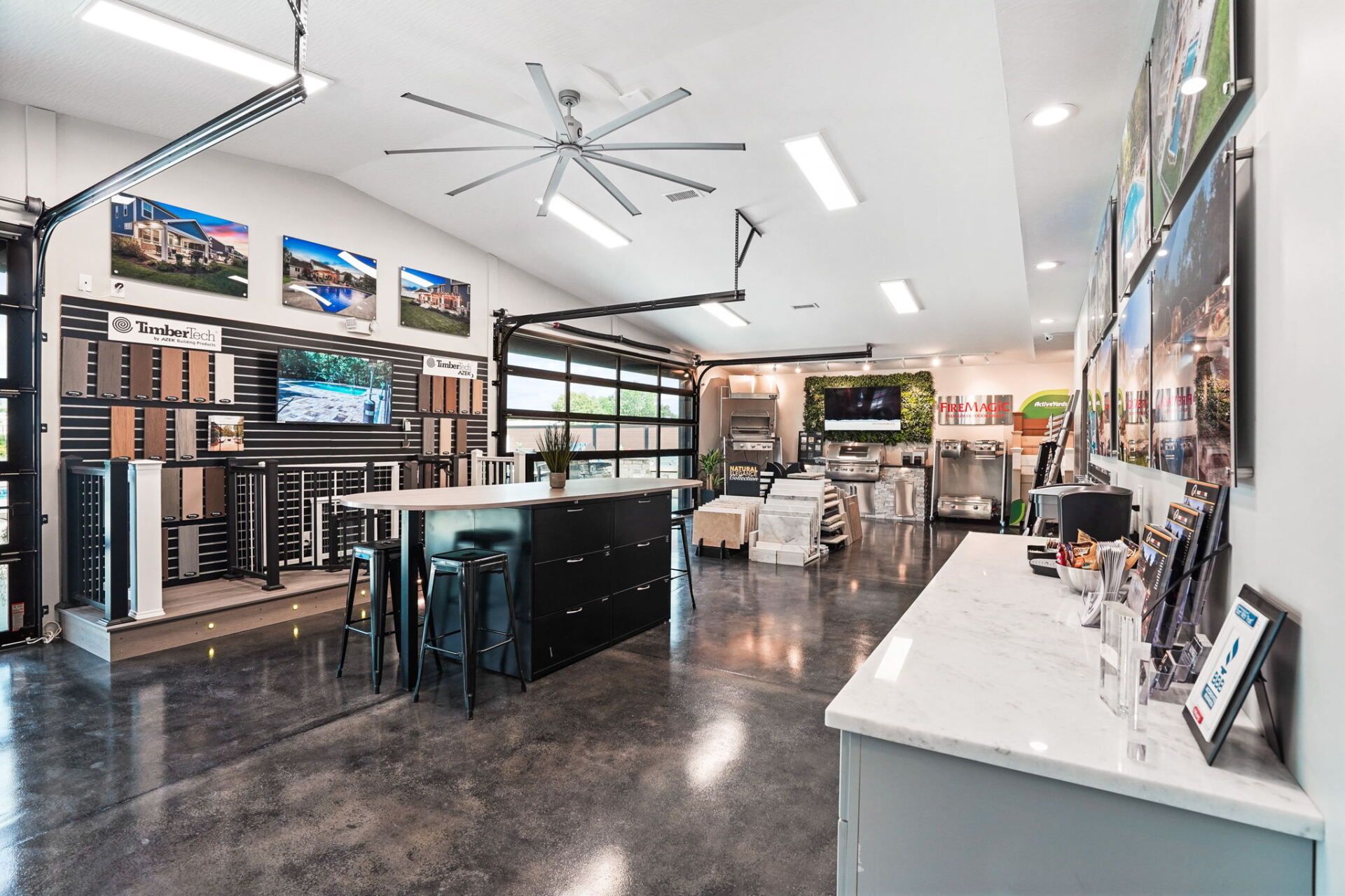 Modern home showroom with polished floor, wall-mounted TVs, and kitchen-style display counters