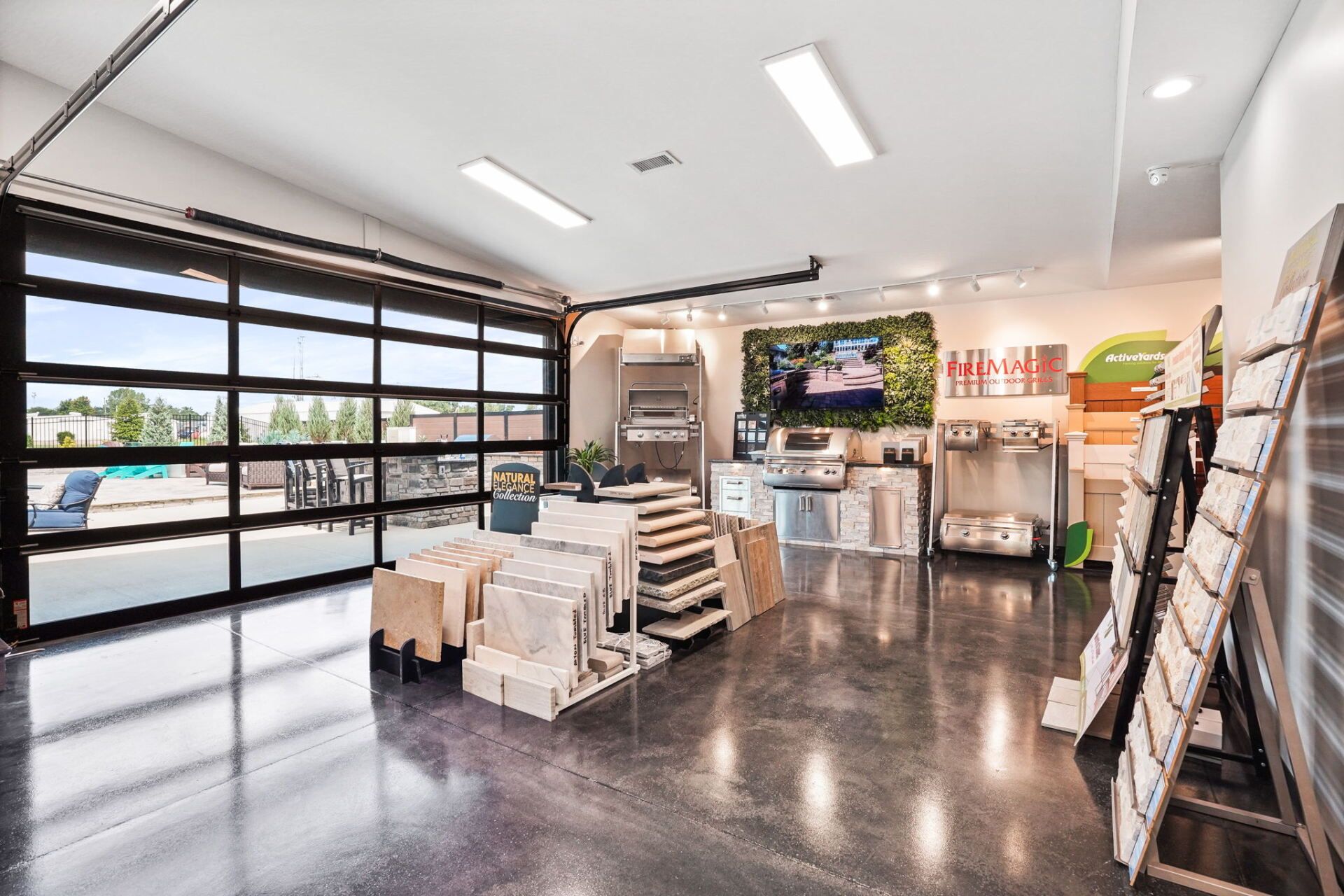 Bright retail showroom with shelves, pallets, and a large glass garage door