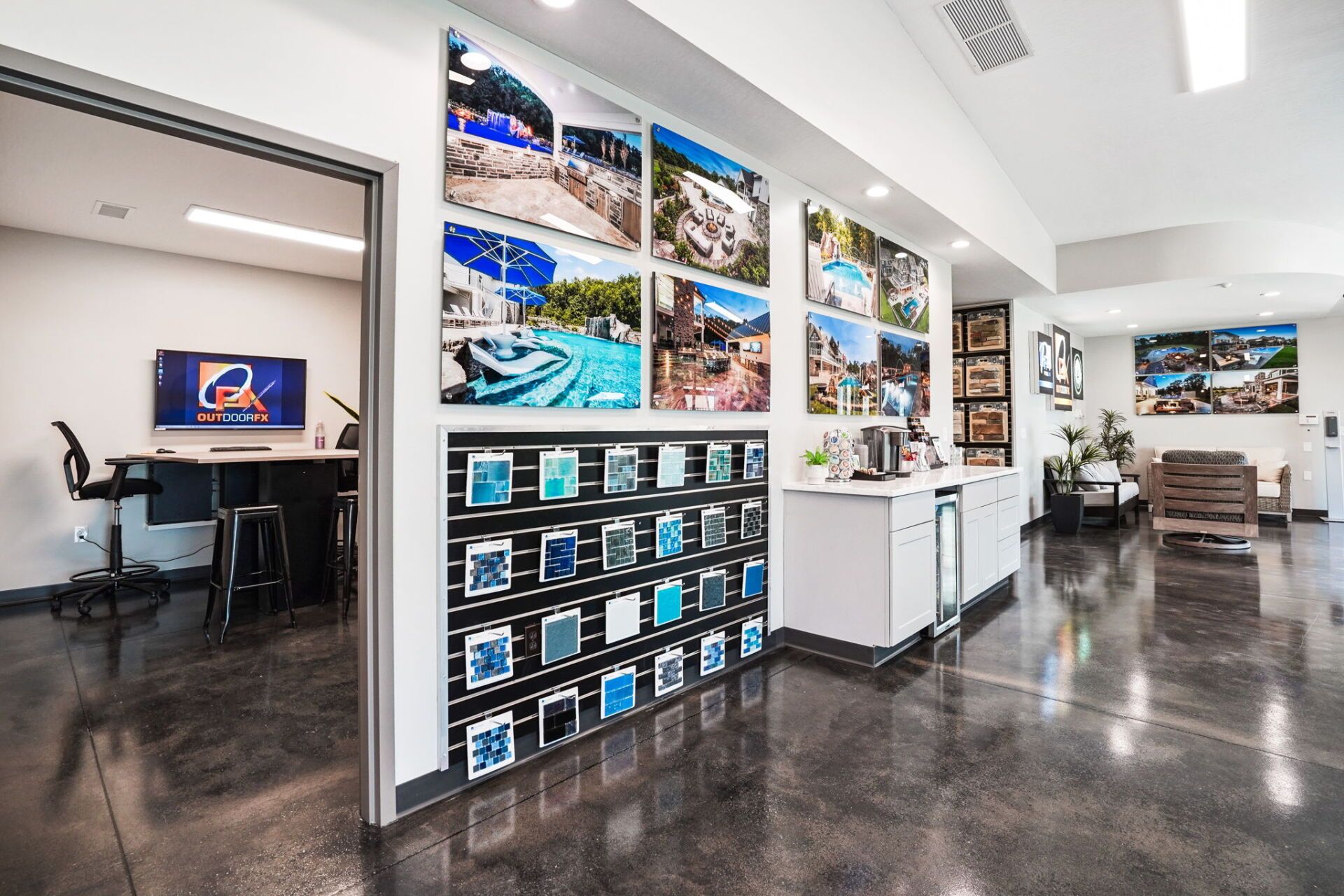 Bright showroom hallway with wall-mounted TVs, display shelves, and glossy floors beneath white lighting