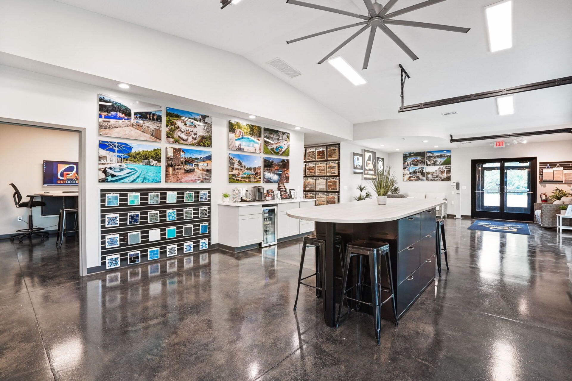 Bright modern art gallery with framed landscape photos, polished concrete floor, tables, and high ceilings