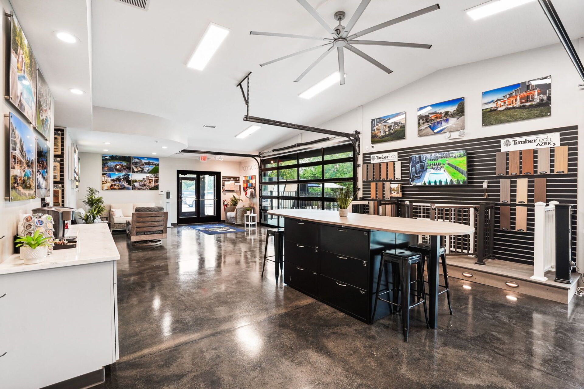 Bright showroom with display walls, black counters, polished floor, and ceiling fans.