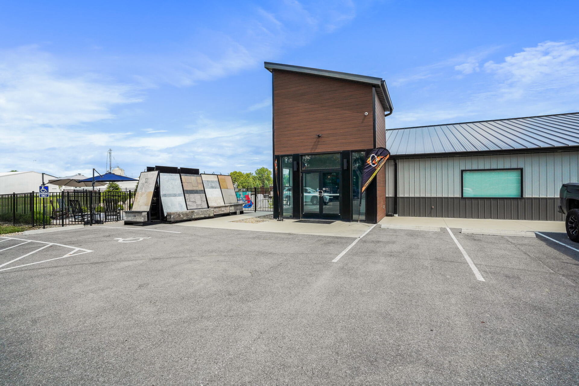 Modern building with glass entrance, brick facade, and empty parking lot under a blue sky