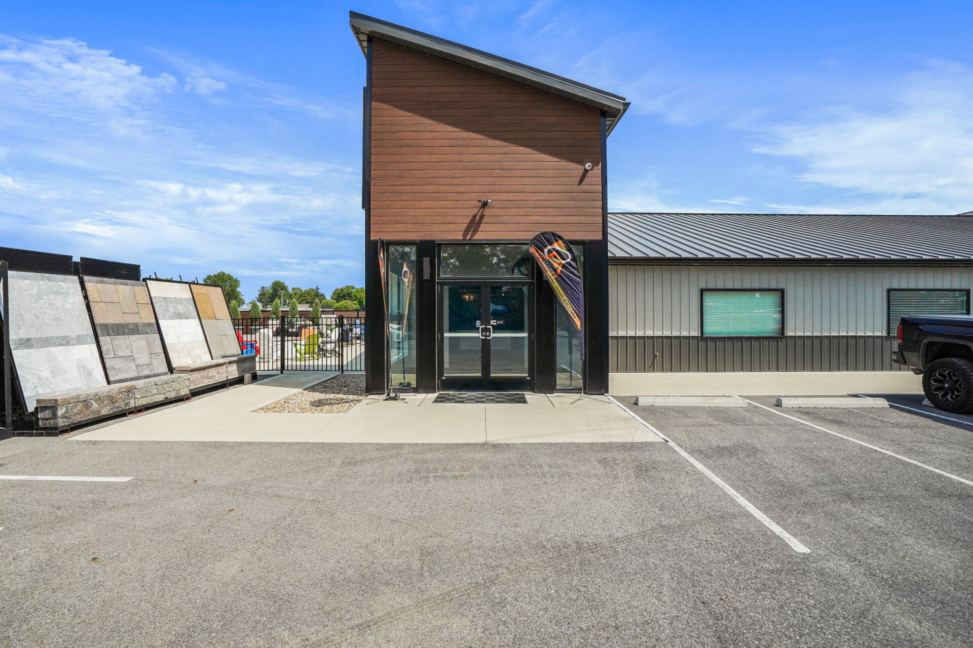Modern building entrance with wood facade, glass doors, and parking lot in front