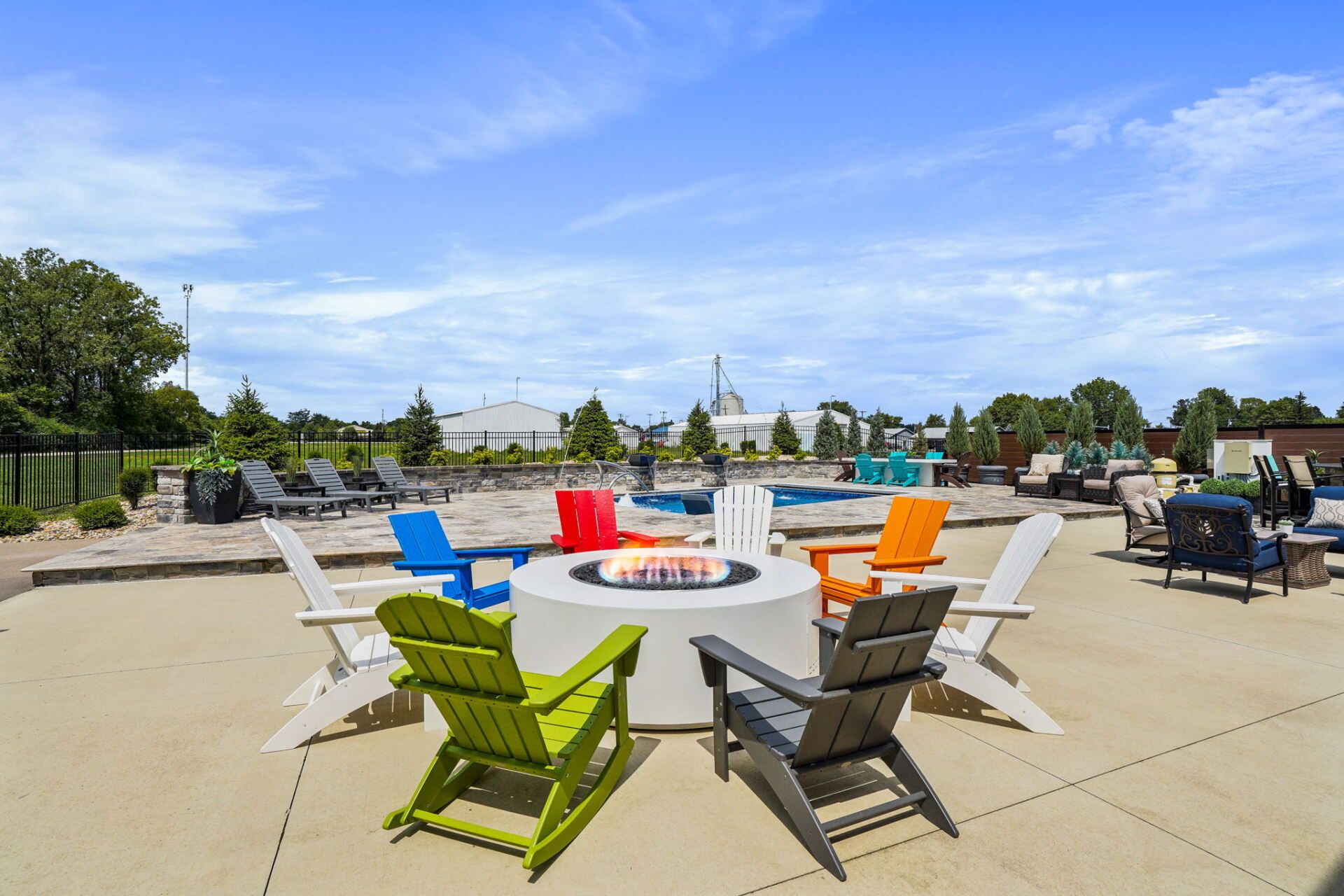 Outdoor patio with colorful lounge chairs around a fire pit under a blue sky