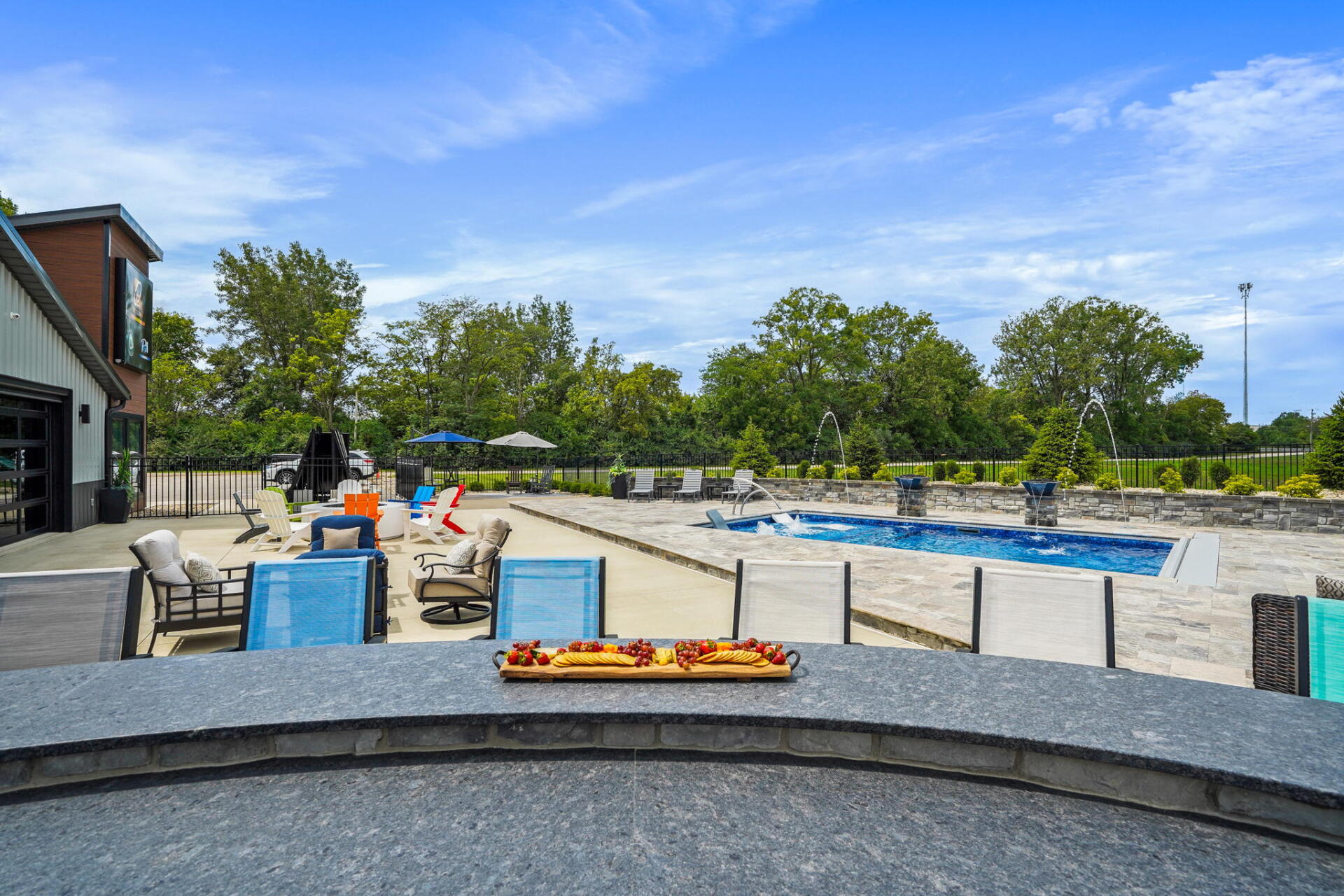 Outdoor pool area with blue lounge chairs, tables, and a small putting green on a sunny day