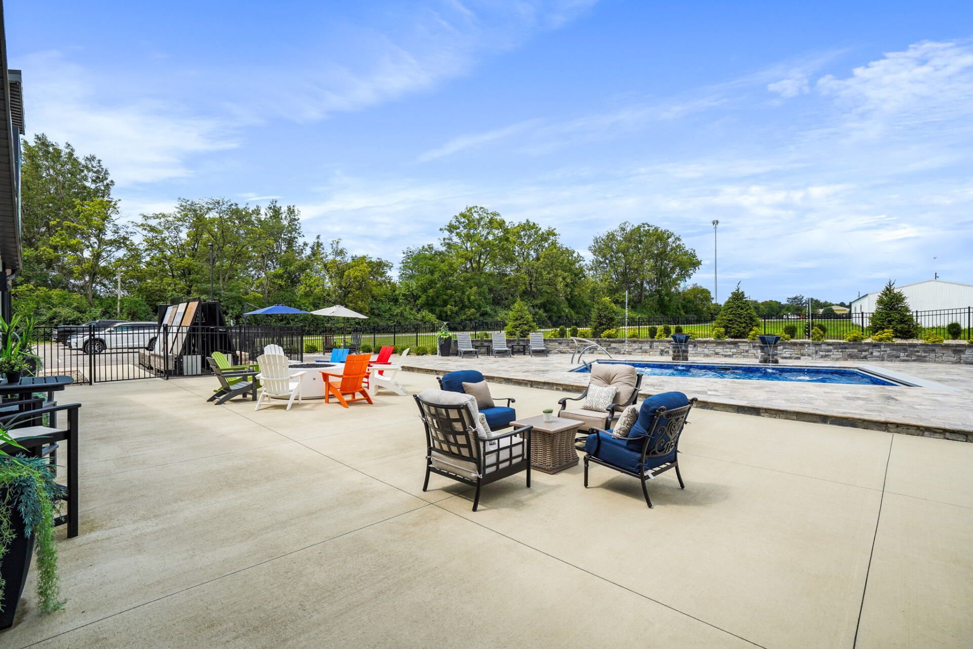 Poolside patio with lounge chairs, umbrella tables, and a blue swimming pool under a clear sky