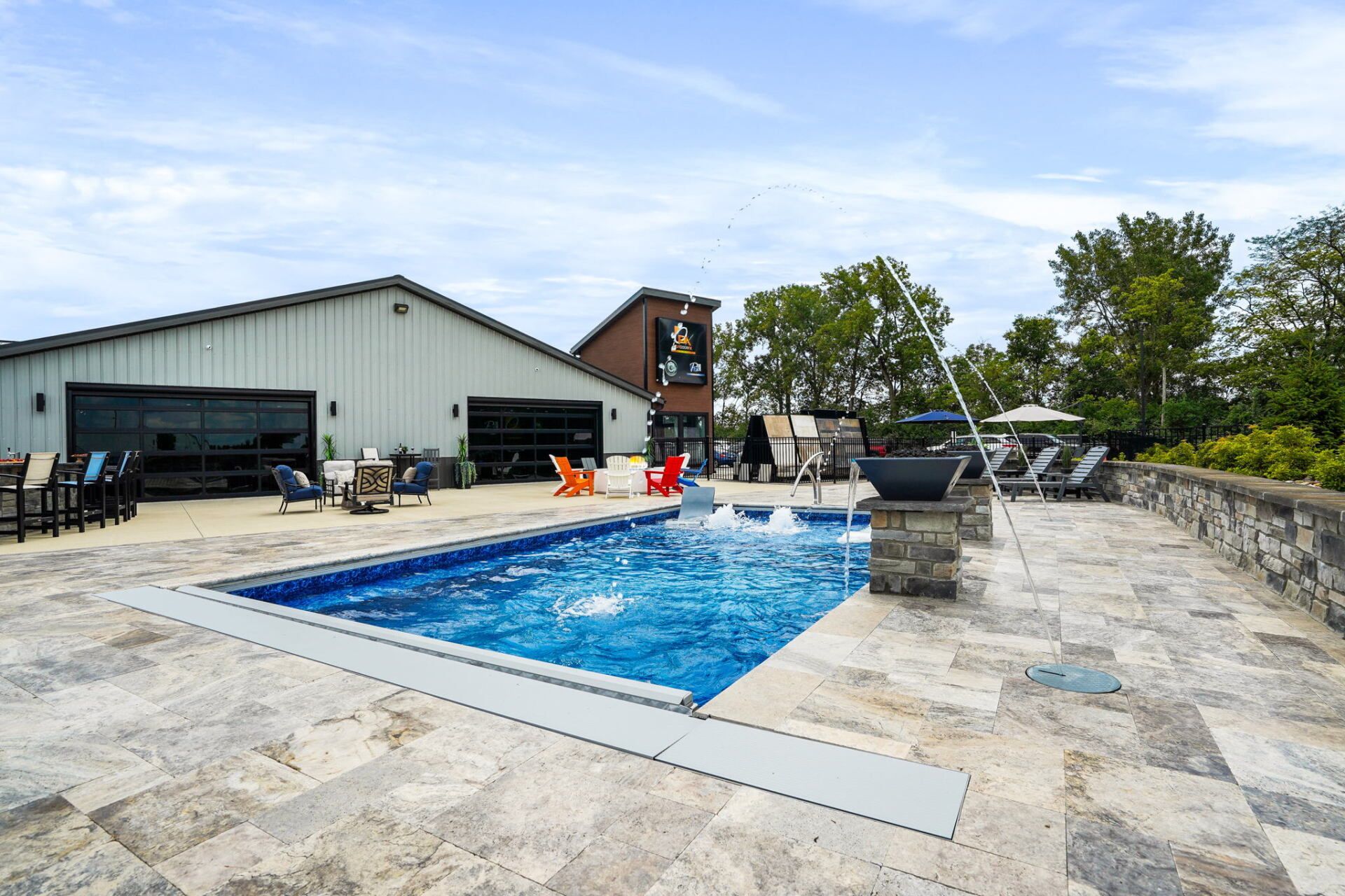 Outdoor pool with stone deck, lounge chairs, and a building in the background