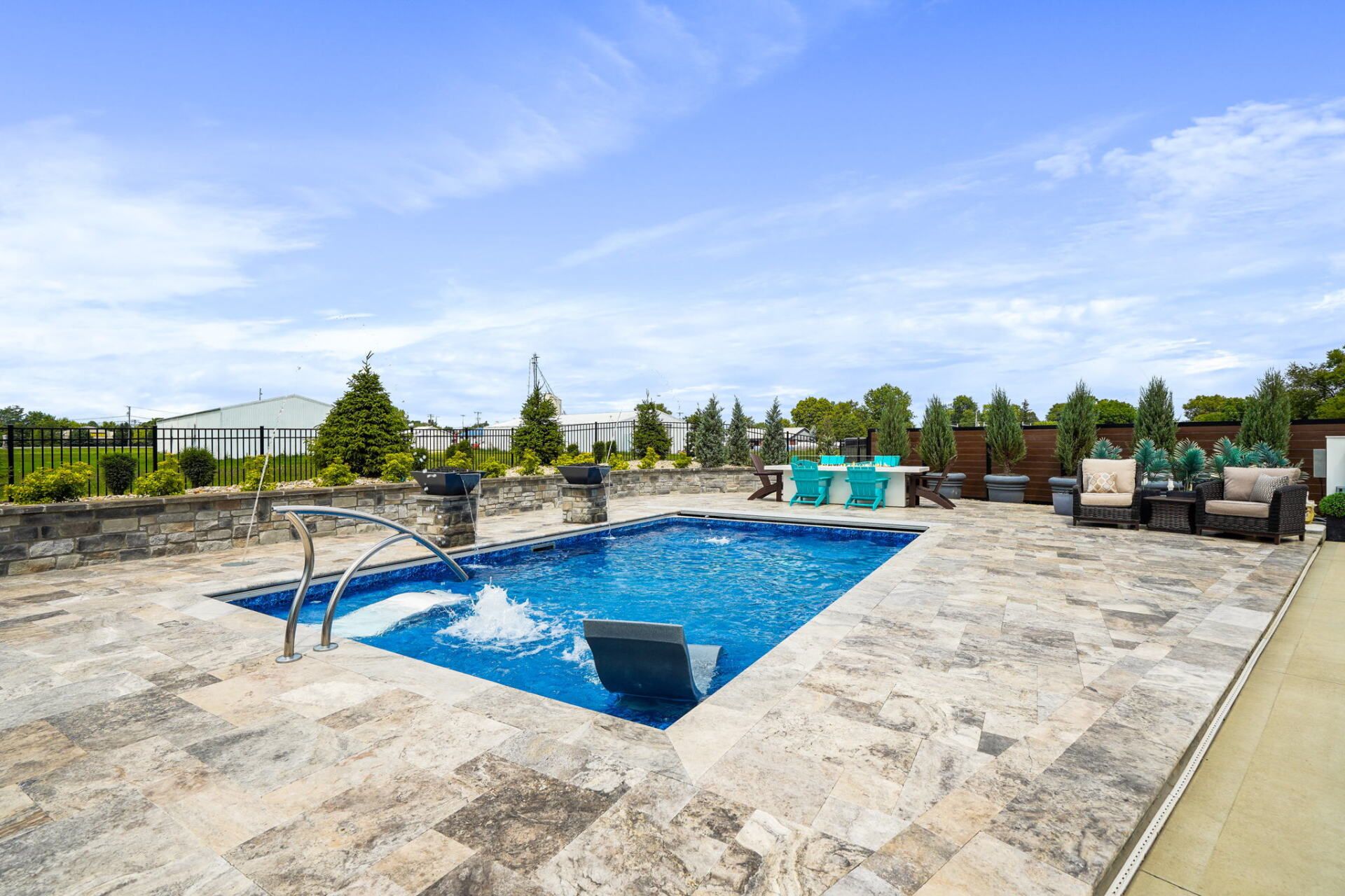 Outdoor swimming pool with stone deck, lounge chairs, and clear blue sky