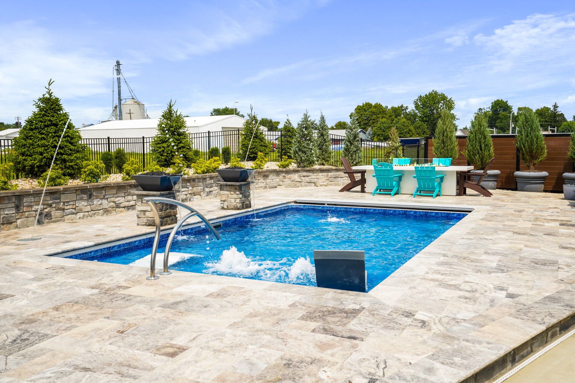 Outdoor patio with a small blue pool, lounge chairs, and a stone deck under a sunny sky