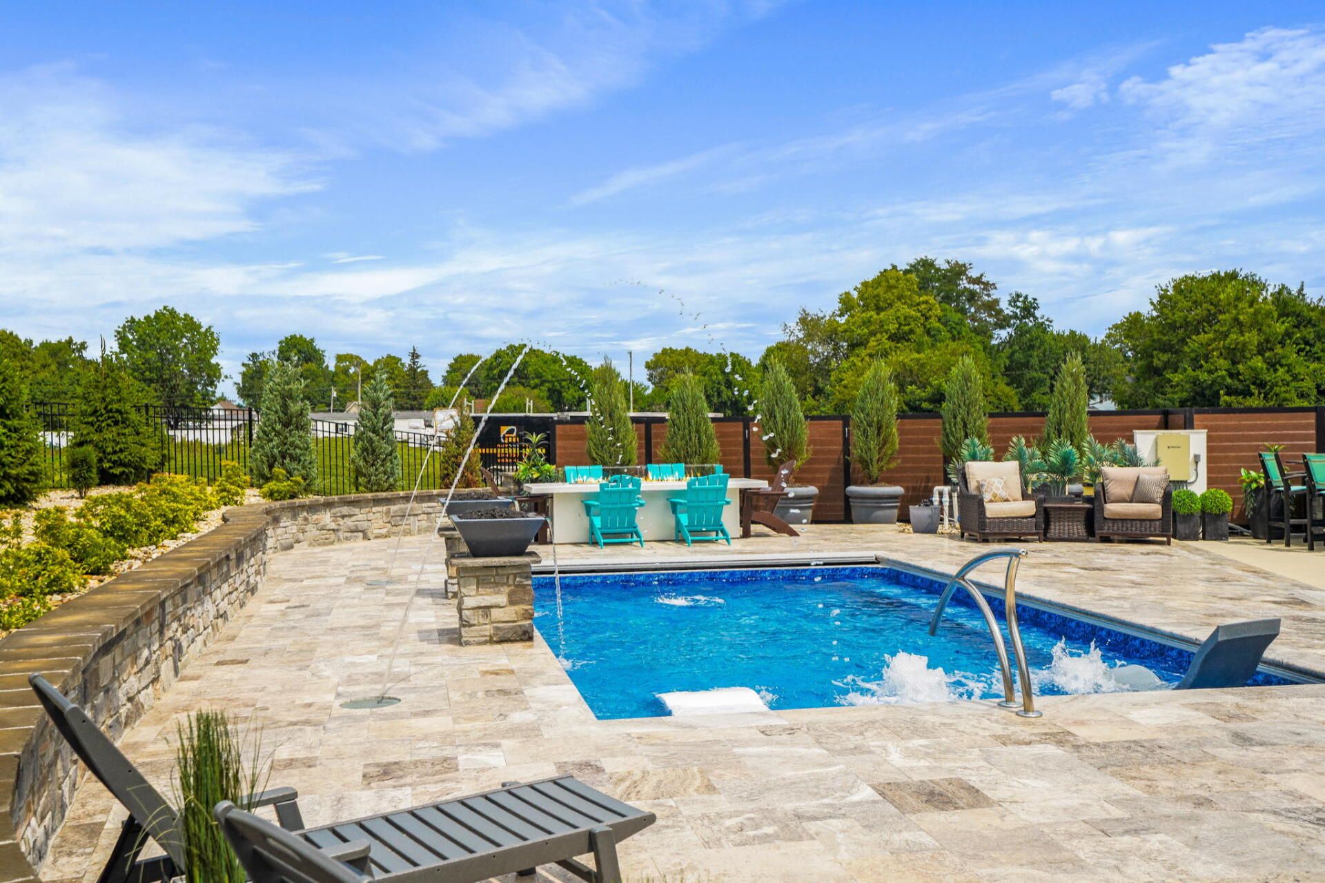 Outdoor pool with stone deck, turquoise lounge chairs, and clear blue sky