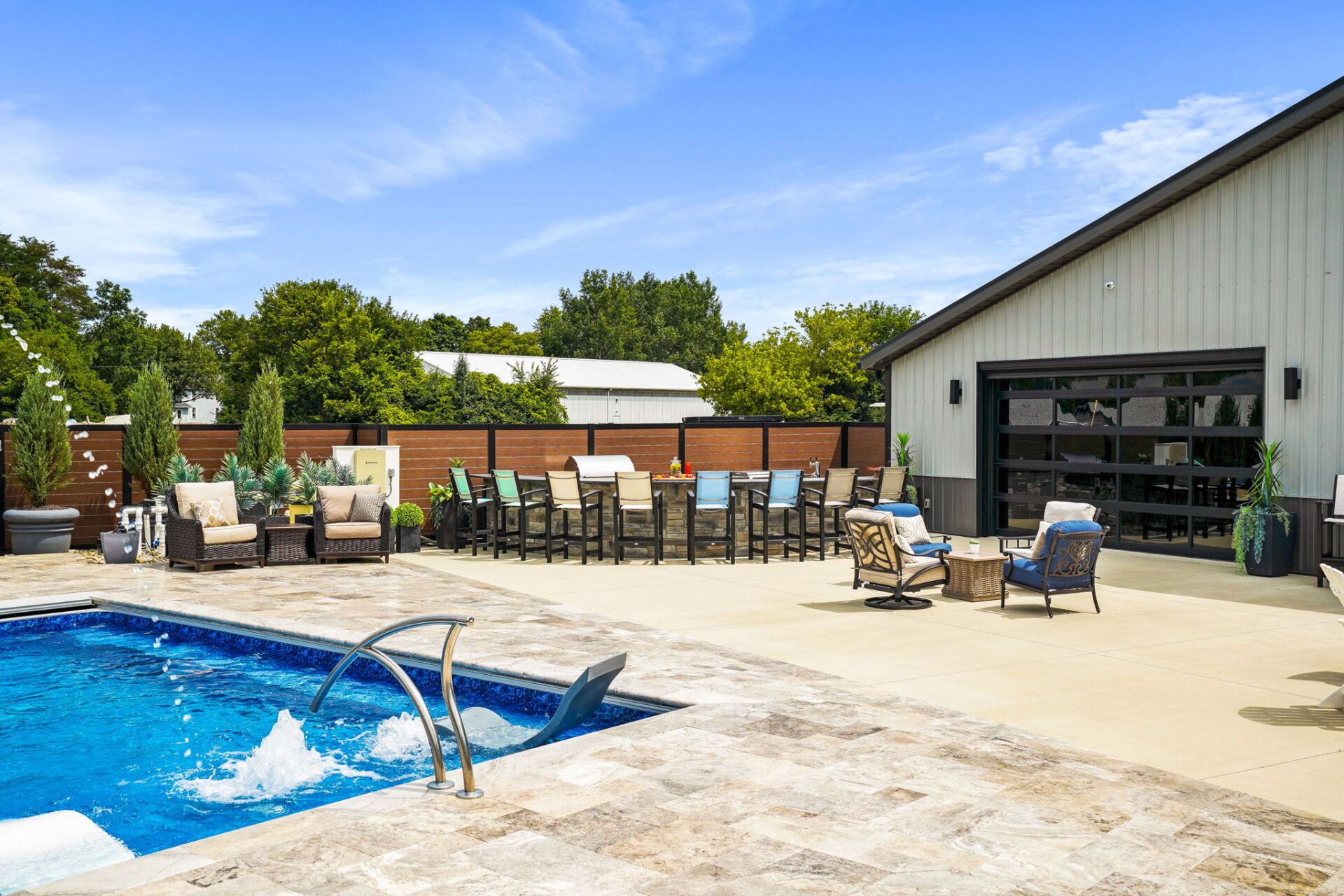 Outdoor pool with patio seating beside a building and clear blue sky