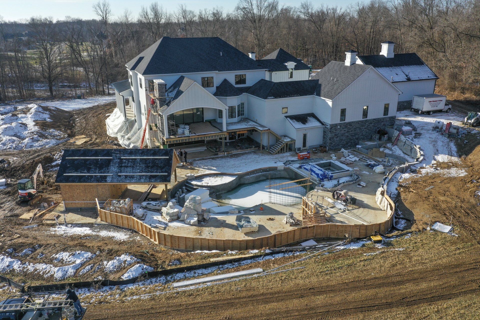 Damaged house with collapsed deck and debris, viewed from above in a snowy yard