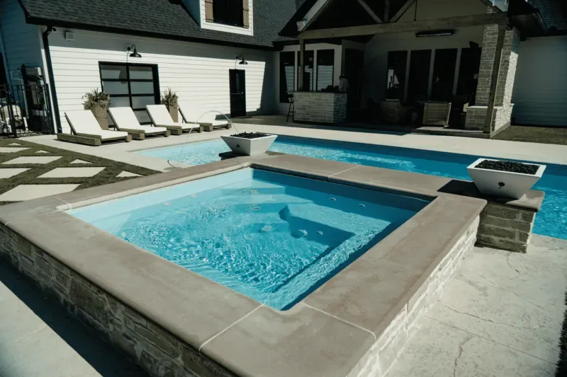 Backyard with a small square pool, lounge chairs, and a covered patio beside a house