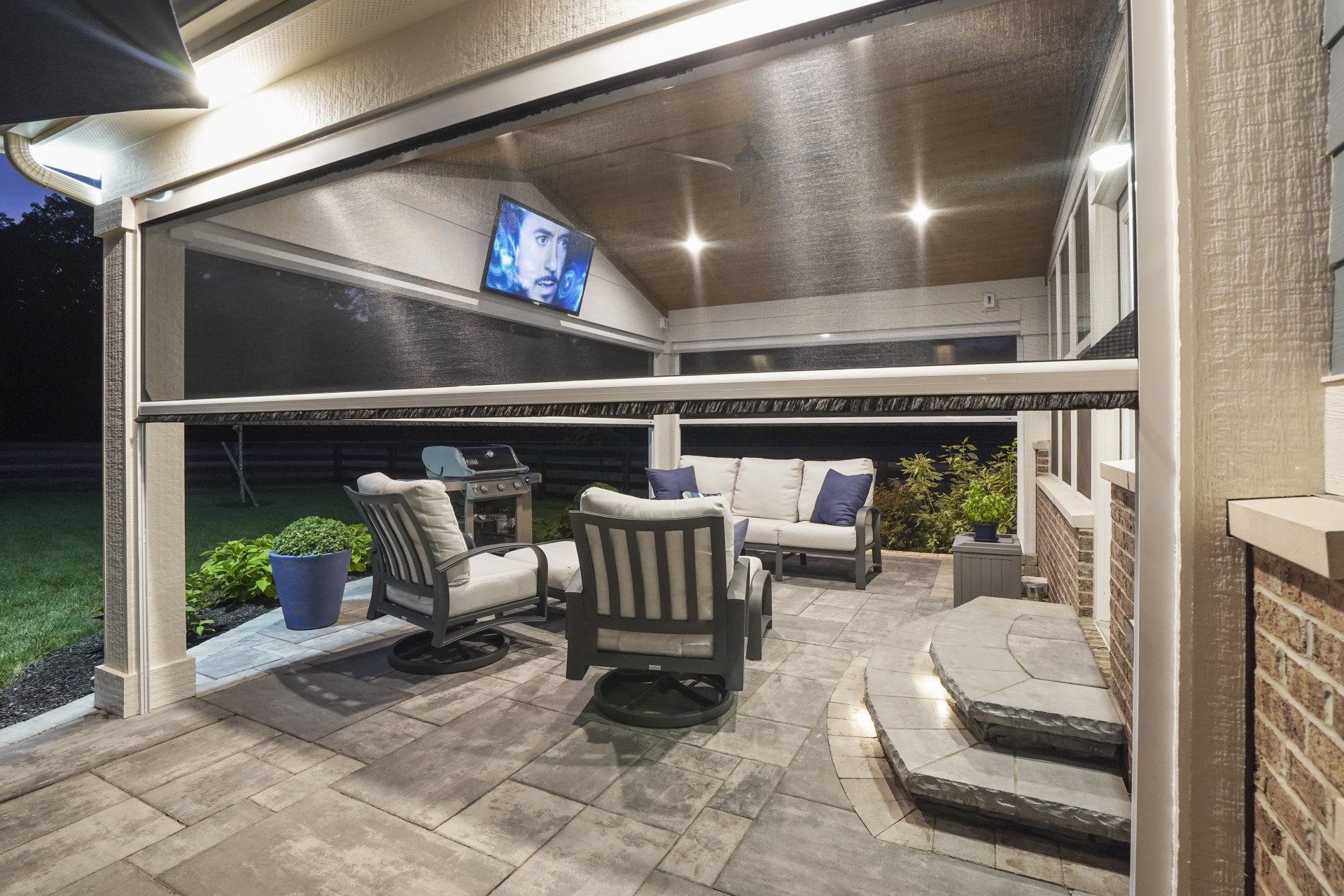 Covered patio with outdoor seating, TV, and string lights at night