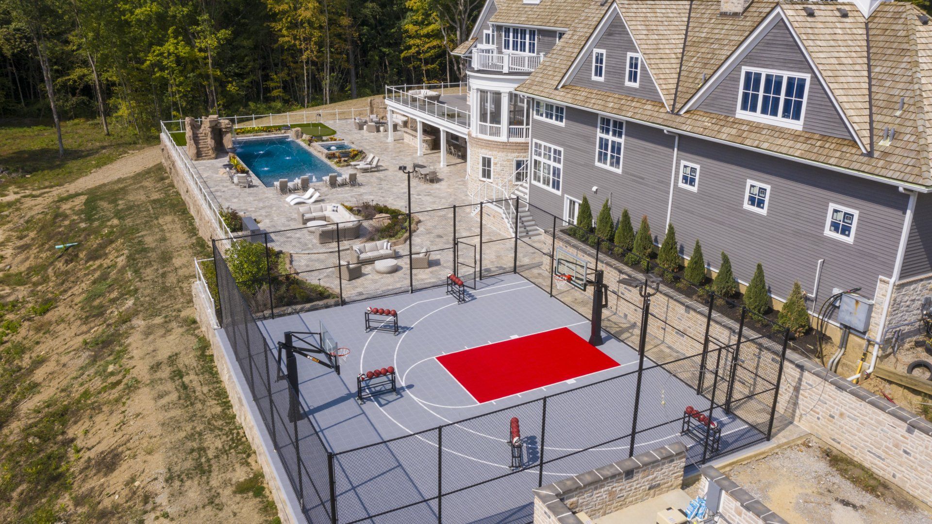 Backyard sport court beside a house with a red center pad and pool in the background