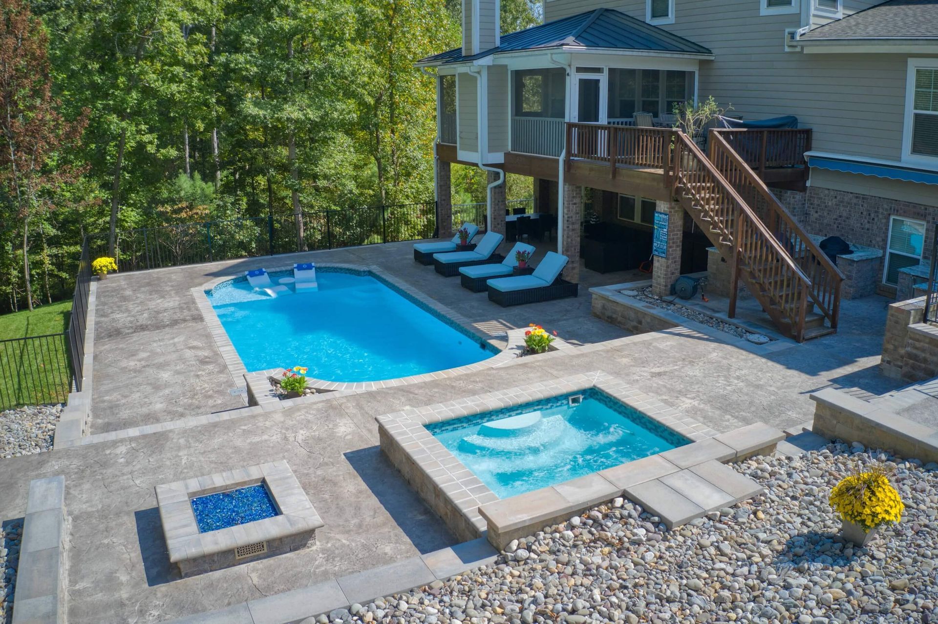 Backyard pool with hot tub, lounge chairs, and a wooden deck beside a house