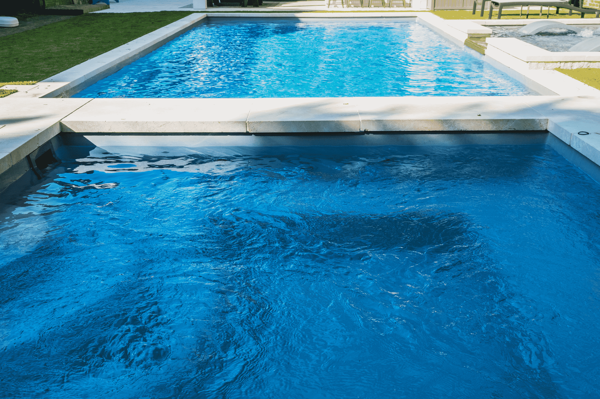 Blue swimming pool with a shallow ledge and clear water in a bright outdoor setting