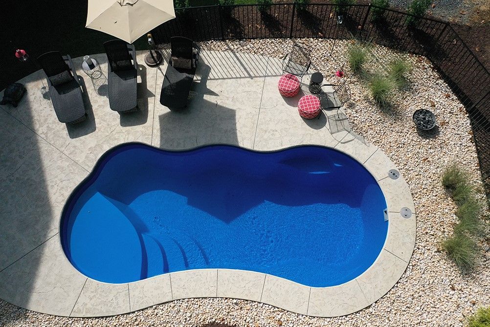 Backyard swimming pool with blue water, patio furniture, and desert landscaping