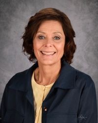 A woman in a blue shirt is smiling for the camera.