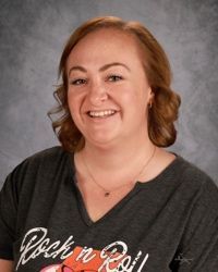 A woman in a plaid shirt is smiling for a picture.