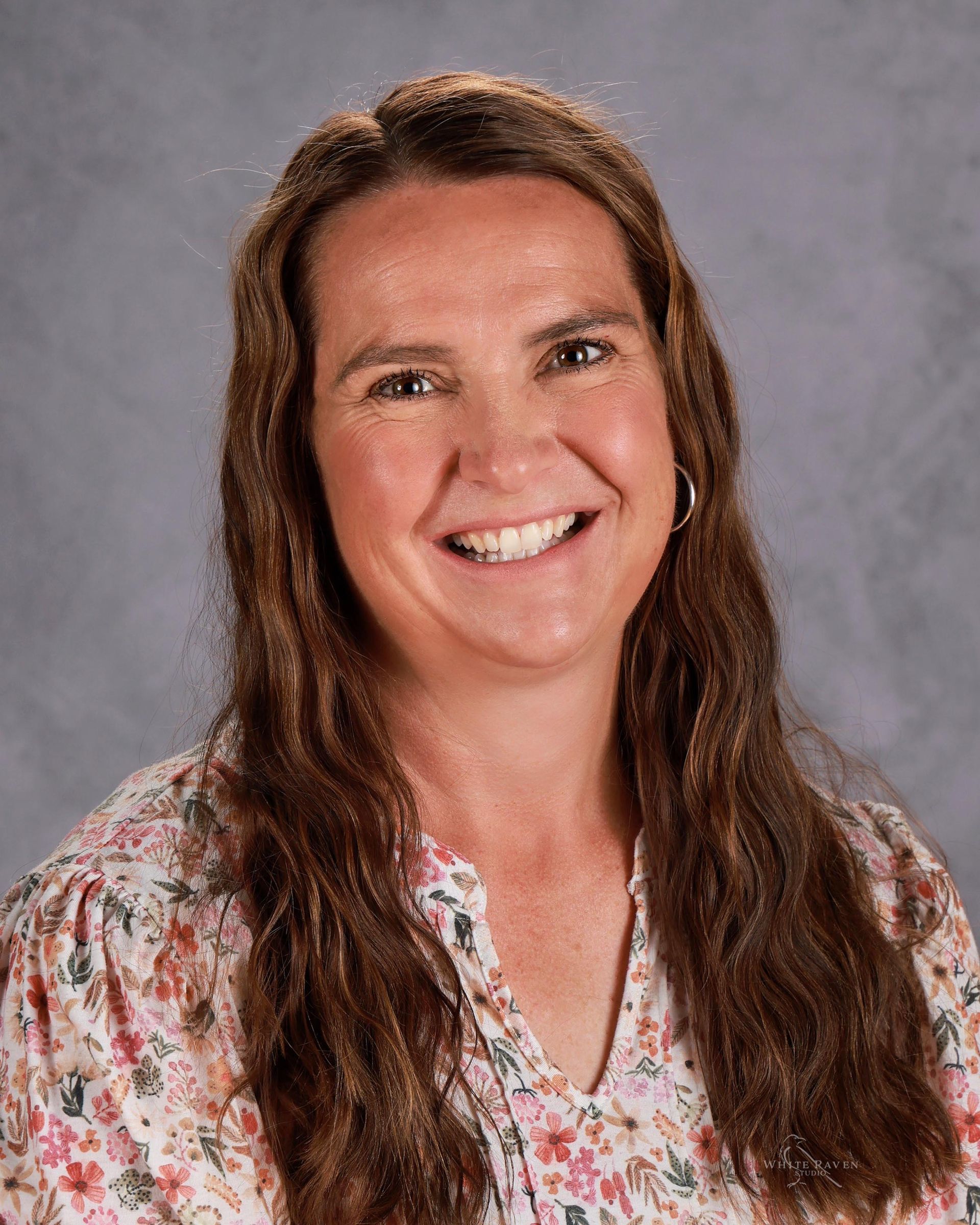 A woman with long brown hair is smiling for a picture.