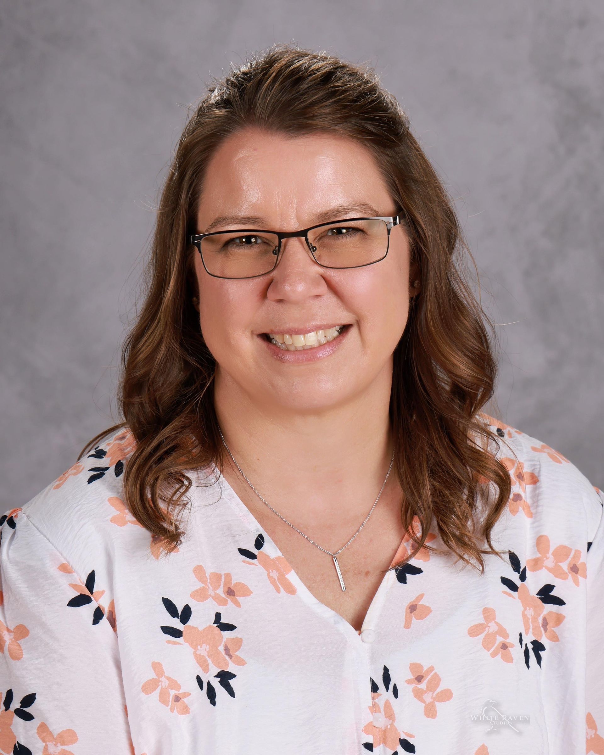 A woman in a white shirt is smiling for the camera.