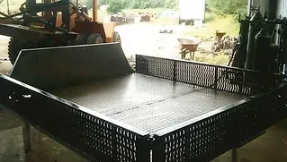 a metal tray is sitting in a garage next to a tractor .