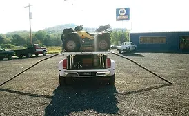 a truck is towing a four wheeler in a parking lot
