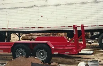 a red trailer is parked next to a white trailer .