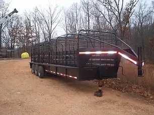 a trailer is parked on a dirt road with trees in the background